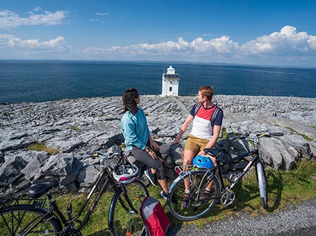 A holiday couple enjoying views of Black Head Lighthouse and the Atlantic Ocean in the Burren, Co Clare © Clare County Council