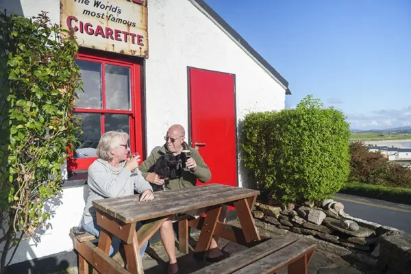 Couple enjoying a drink with their dog at Fisk Seafood Bar in Downings County Donegal © Failte Ireland