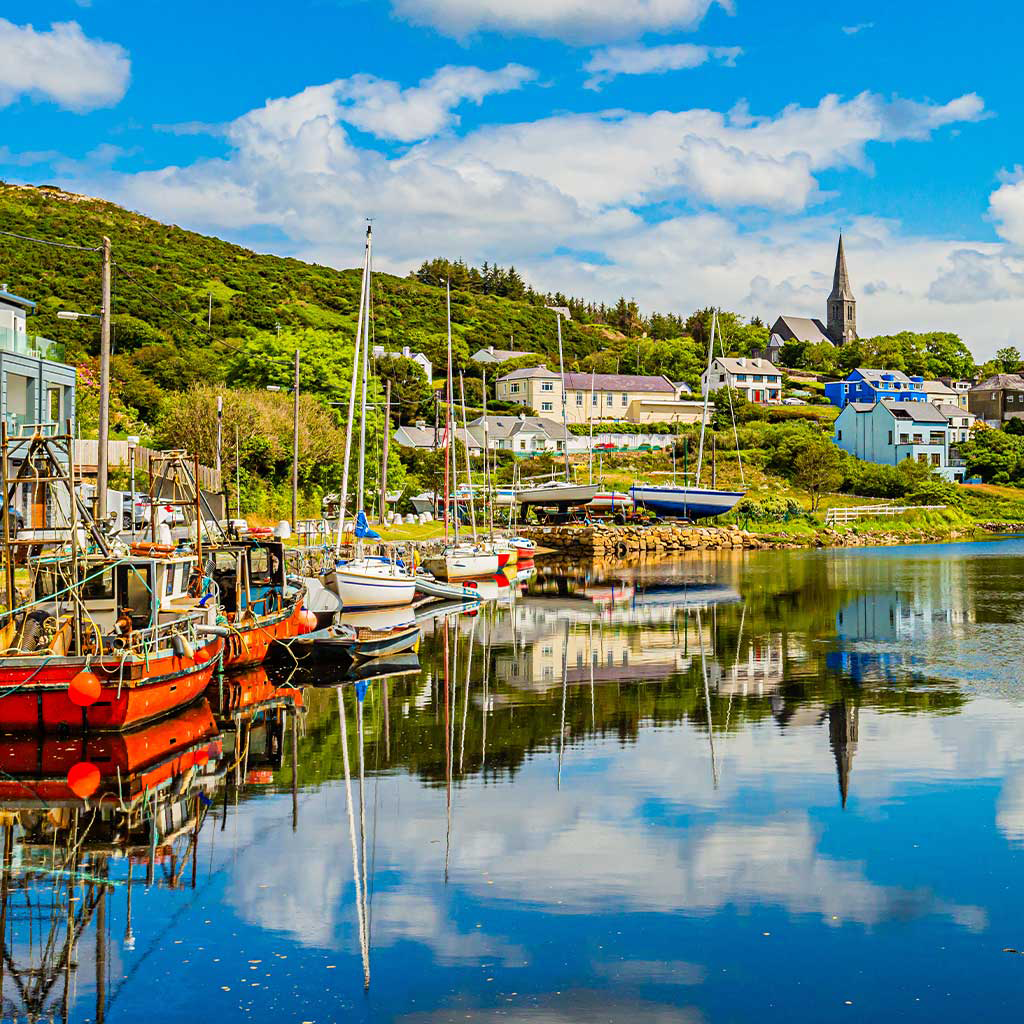 Pier at the port of Clifden at high tide with colourful fishing boat in Galway © Adobe Stock